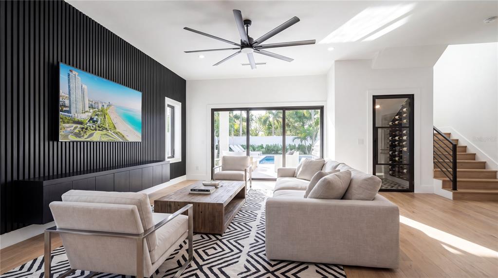 A modern living room features a slatted black accent wall, a large television, and a wine cellar — 2605 W CLEVELAND STREET, TAMPA, FL