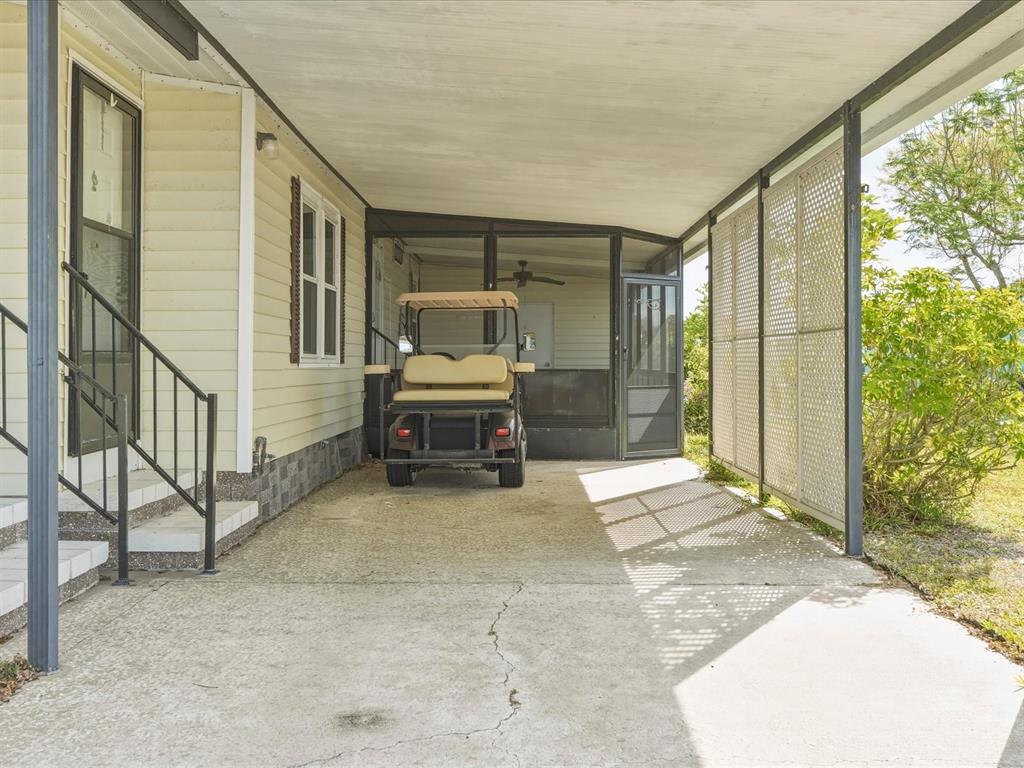 A golf cart is parked under a covered carport next to a house with stairs — 6144 REDWING AVENUE, ENGLEWOOD, FL