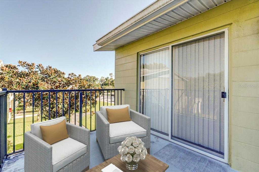 A balcony with two wicker chairs, a small table, and a sliding glass door — 1213 UNITAH AVENUE UNIT 2, LAKELAND, FL