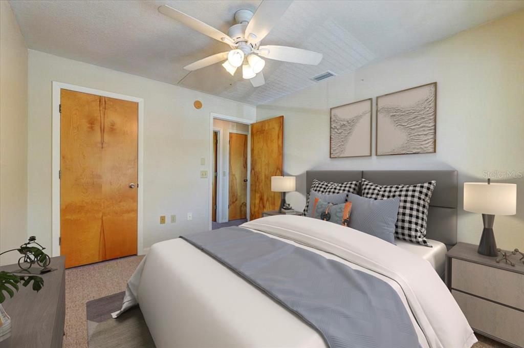 A bedroom features a bed with gray bedding, two lamps, and wooden doors — 1213 UNITAH AVENUE UNIT 2, LAKELAND, FL