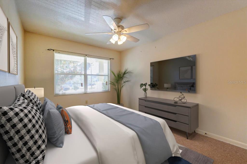 A bedroom features a bed with patterned pillows, a gray dresser, and a wall-mounted television — 1213 UNITAH AVENUE UNIT 2, LAKELAND, FL