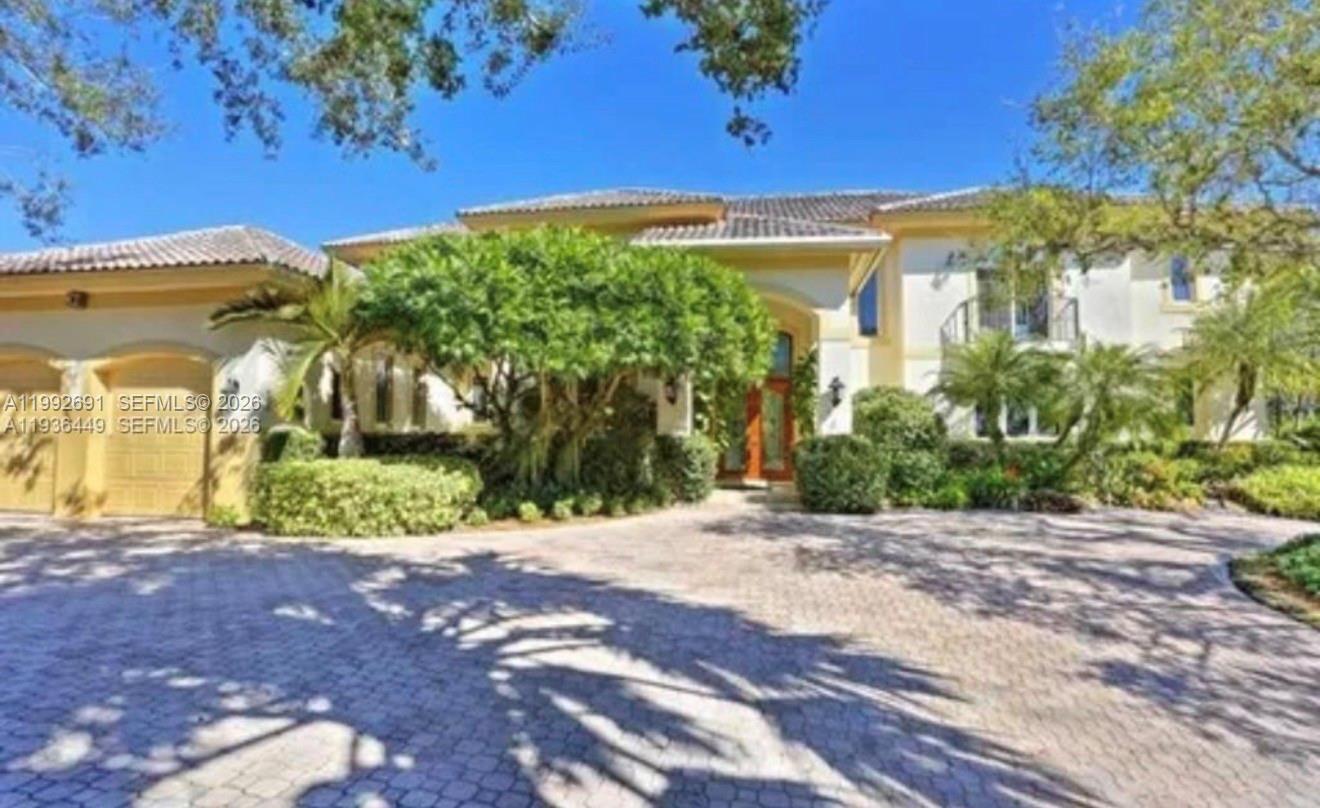 A two-story house with a paved circular driveway, a three-car garage, and lush landscaping — 673 Destacada Ave, Coral Gables FL 33156, CORAL GABLES, FL