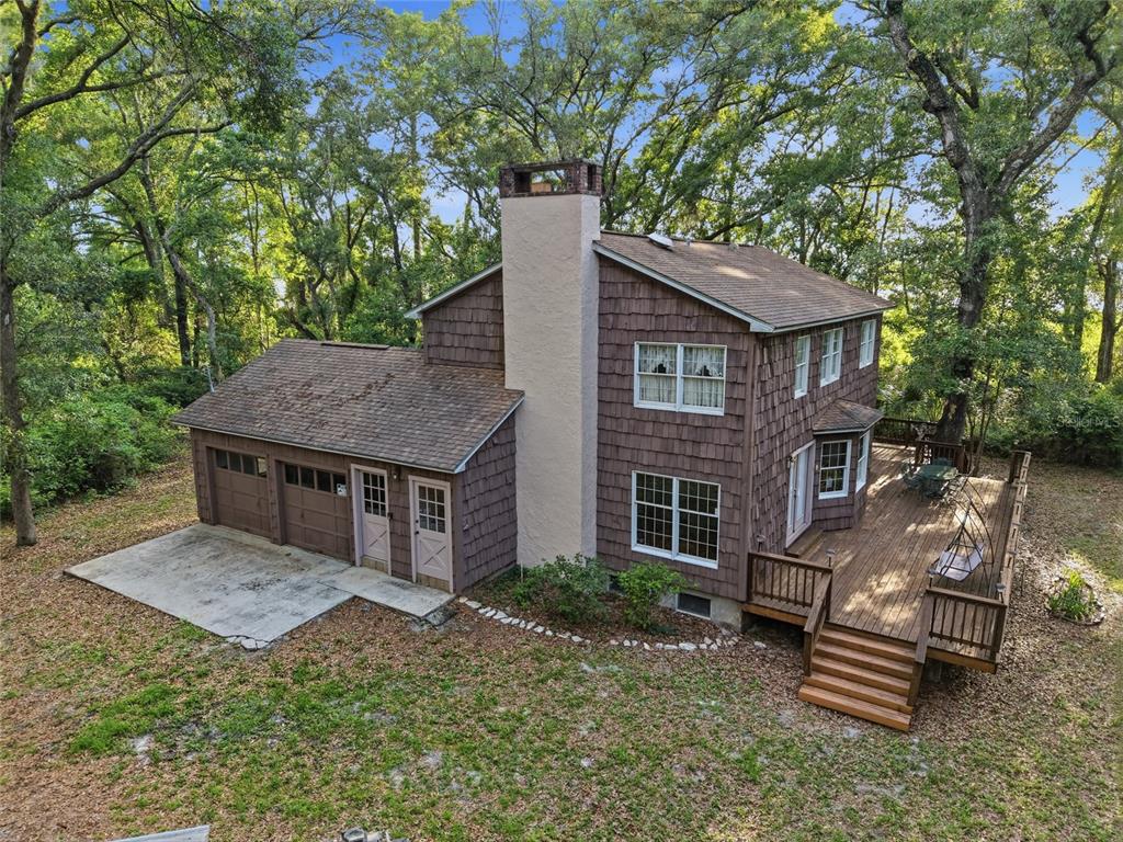 An elevated view of a two-story brown shingle house with a large wooden deck — 9291 NW 127TH PLACE, CHIEFLAND, FL
