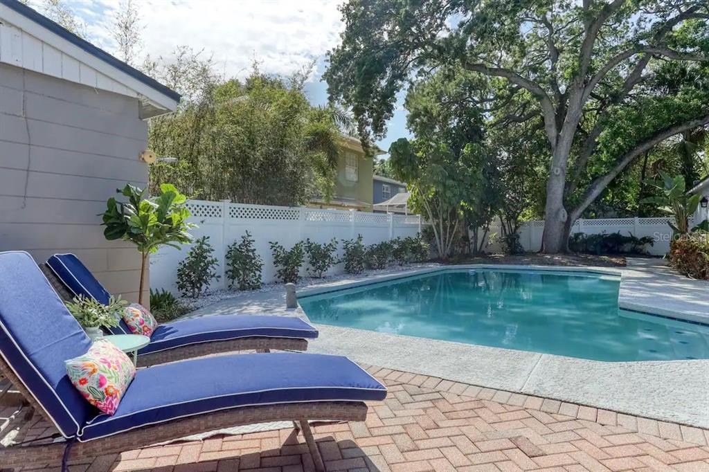 A backyard features a swimming pool, brick patio, two lounge chairs, and a white fence — 4014 W PALMIRA AVENUE, TAMPA, FL