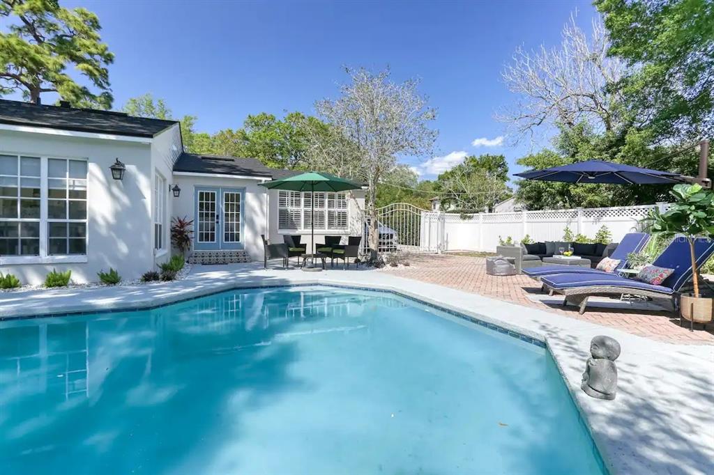 A backyard swimming pool with a brick patio, lounge chairs, and a white house exterior — 4014 W PALMIRA AVENUE, TAMPA, FL