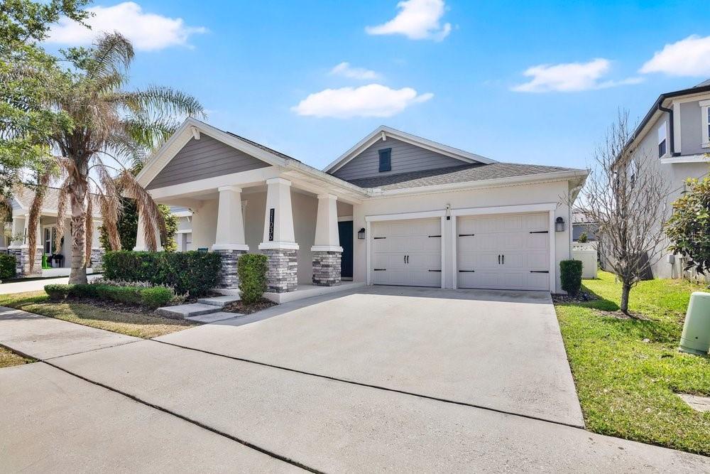 A single-story suburban house with a two-car garage, stone-accented columns, and a covered porch — 11036 ROBERT FROST DRIVE, WINTER GARDEN, FL