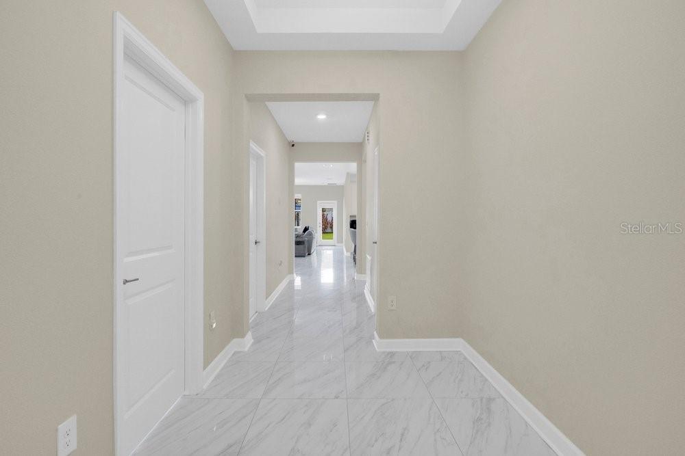 A bright hallway features light-colored marble-look tile flooring and white trim against neutral walls — 11036 ROBERT FROST DRIVE, WINTER GARDEN, FL