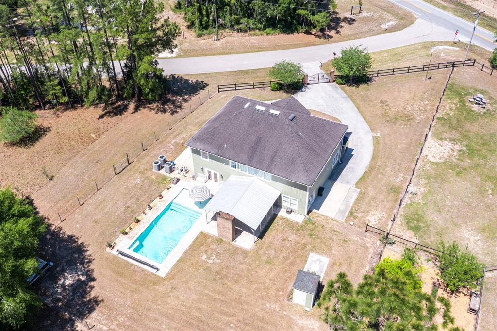 An aerial view shows a house with a swimming pool, covered patio, and fenced yard — 101 RAMSEY DRIVE, MELROSE, FL