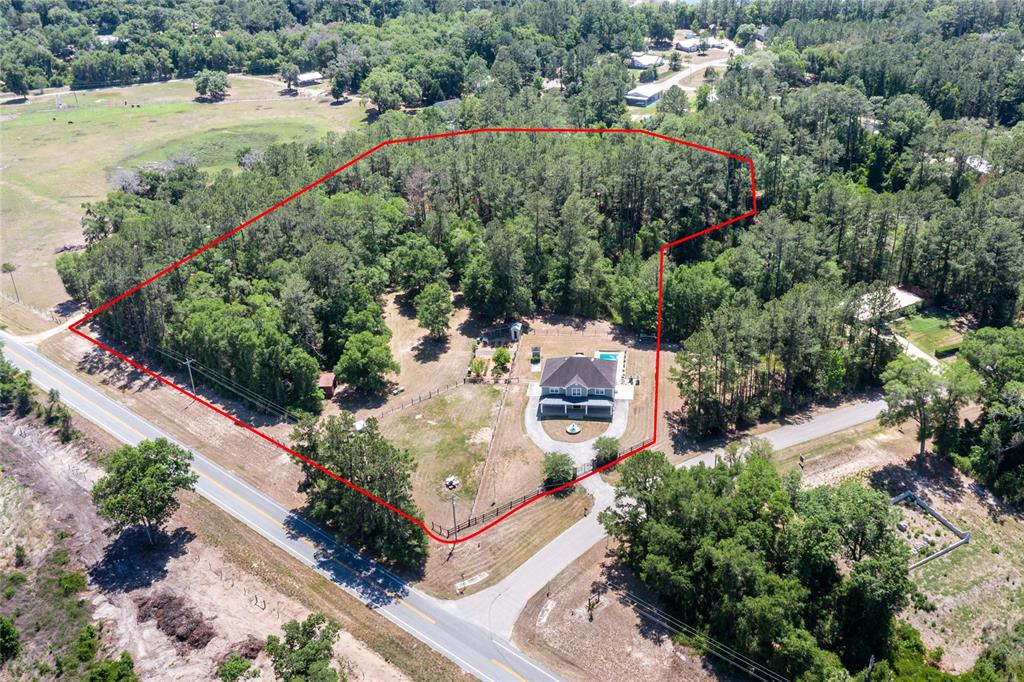 An aerial view shows a house with a pool on a large, partially wooded lot — 101 RAMSEY DRIVE, MELROSE, FL