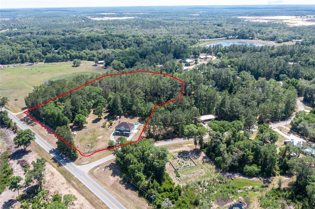 An aerial view shows a house with a pool situated on a large, wooded lot — 101 RAMSEY DRIVE, MELROSE, FL