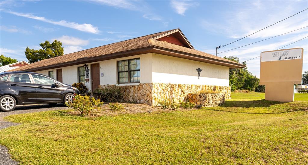 A single-story building with a stone-veneer base, a brown roof, and a prominent signage board — 915 E ALFRED STREET, TAVARES, FL