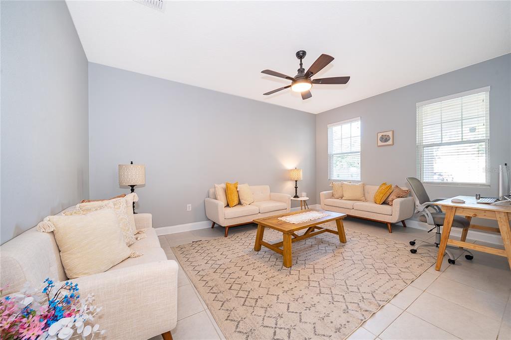 A living room features three light-colored sofas, a wooden coffee table, and a desk area — 8031 NAVEL ORANGE LANE, WINTER GARDEN, FL