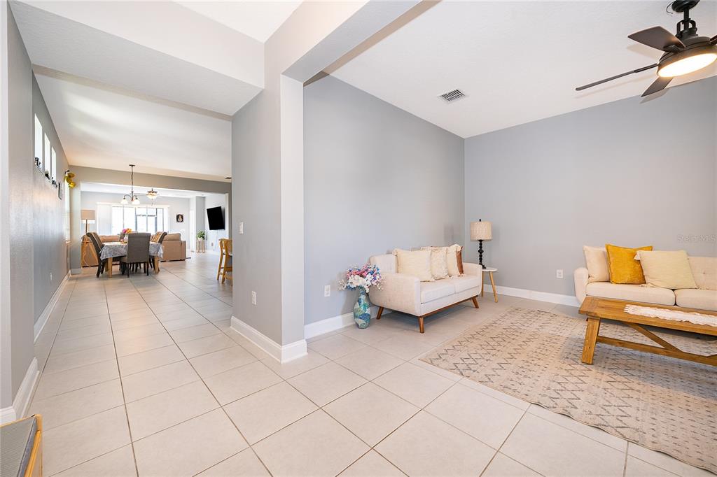 A living room with light gray walls and tile flooring opens into a dining area — 8031 NAVEL ORANGE LANE, WINTER GARDEN, FL