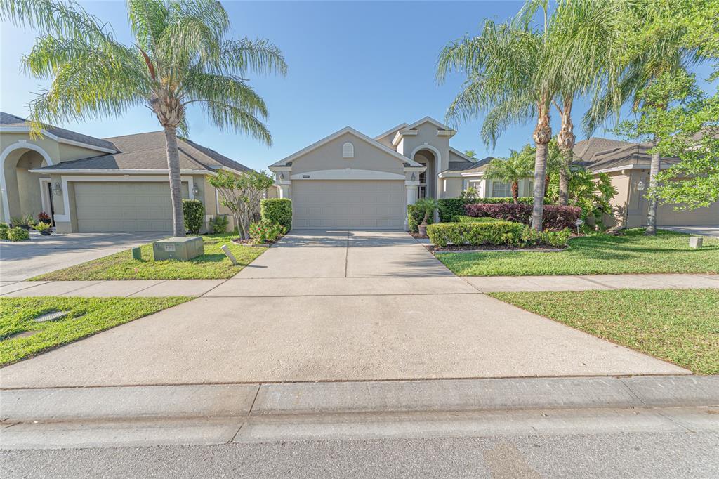 A single-story suburban house with a concrete driveway, two-car garage, and palm trees — 14921 BRAYWOOD TRAIL, ORLANDO, FL