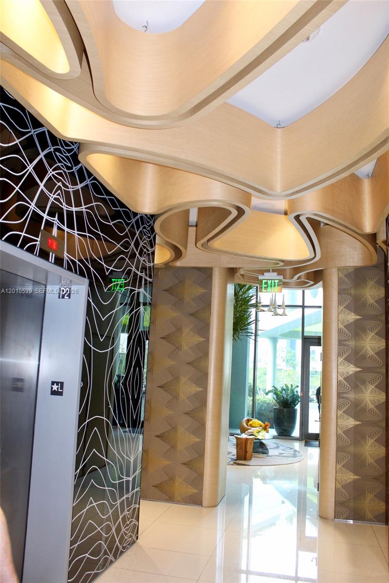 A lobby area features a sculptural wooden ceiling, patterned walls, and a stainless steel elevator — 501 NE 31st St # 2705, Miami FL 33137, MIAMI, FL