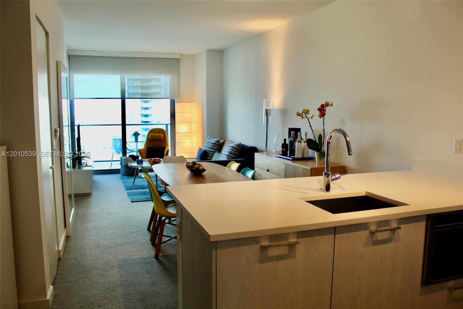 A modern kitchen island with a sink overlooks a dining area and living room — 501 NE 31st St # 2705, Miami FL 33137, MIAMI, FL