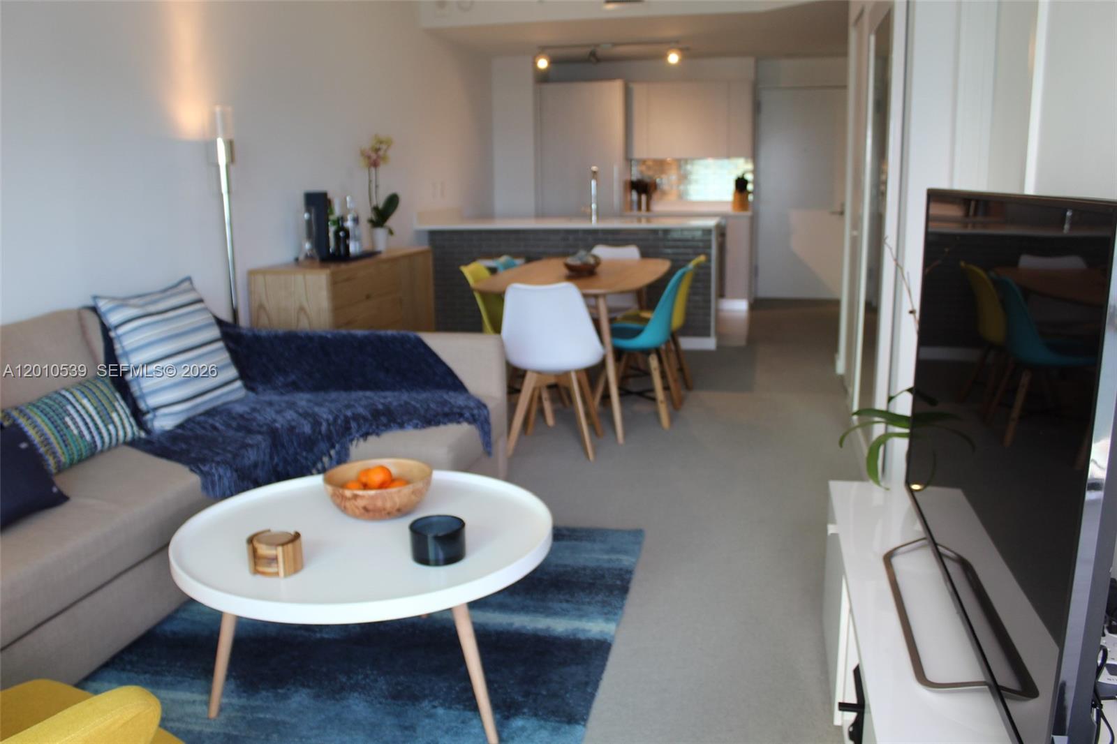 A living room with a sofa, coffee table, and dining area leads to an open kitchen — 501 NE 31st St # 2705, Miami FL 33137, MIAMI, FL