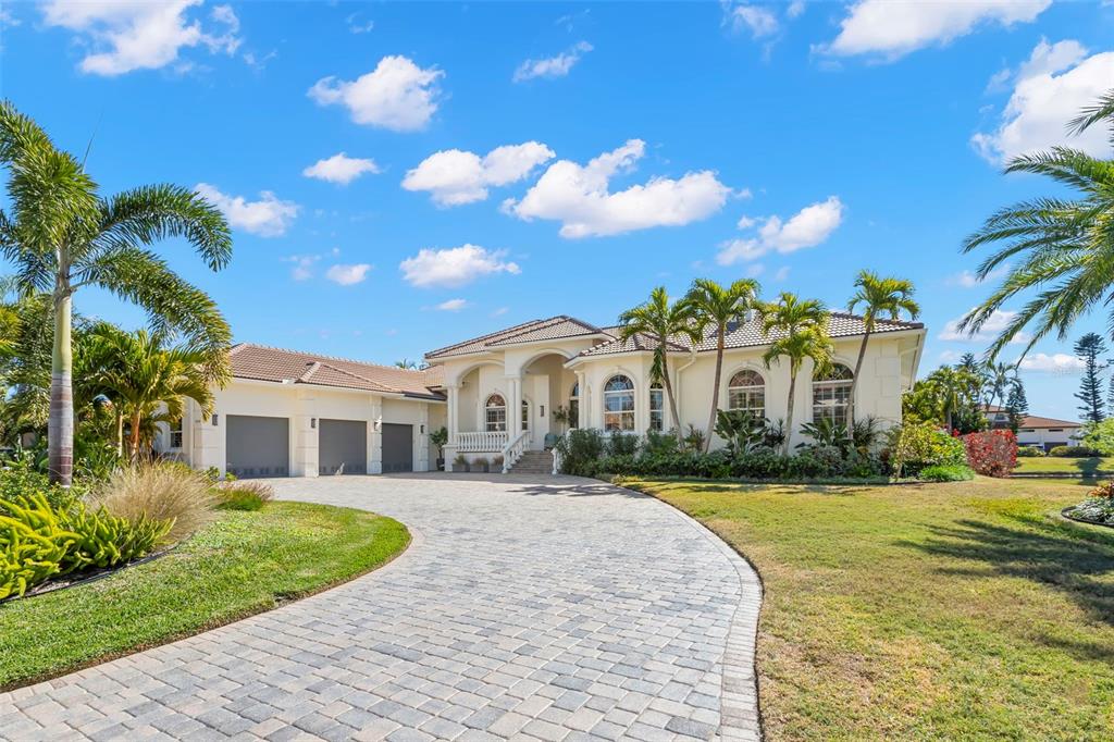 A single-story house with a paved driveway, three-car garage, and palm trees under a blue sky — 5264 61ST AVENUE S, ST PETERSBURG, FL