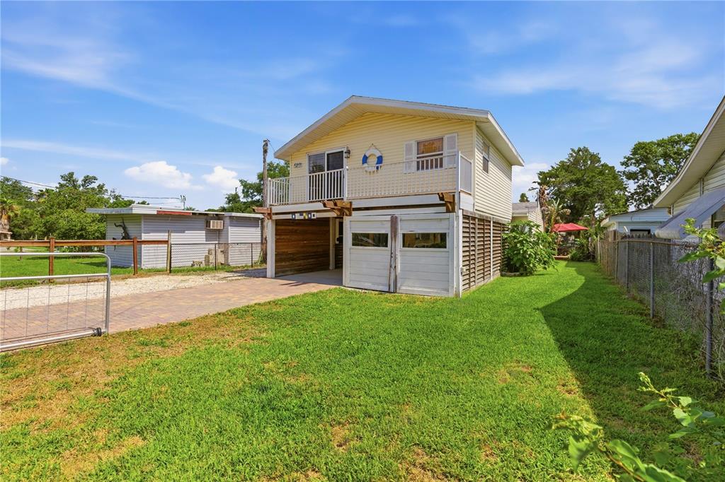 A two-story house with yellow siding, a raised deck, and a ground-level garage area — 5251 ALPACA DRIVE, WEEKI WACHEE, FL