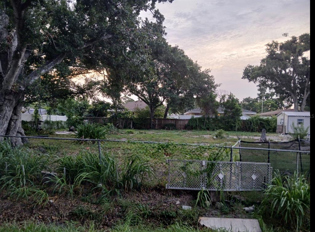 A fenced, grassy residential lot features several large trees and a small shed in back — 4116 LOCUST AVENUE, SARASOTA, FL