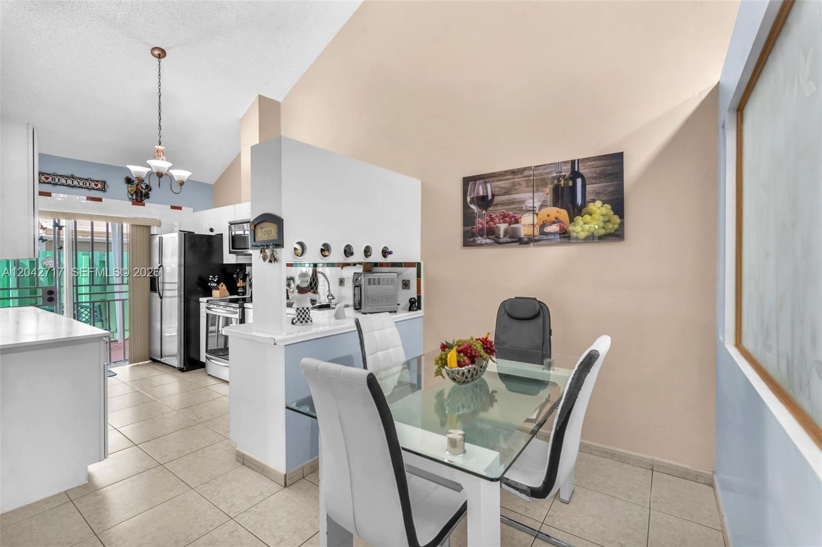 A dining area with a glass table sits adjacent to a kitchen with white cabinets — 9018 NW 120th St # 133, Hialeah Gardens FL 33018, HIALEAH GARDENS, FL