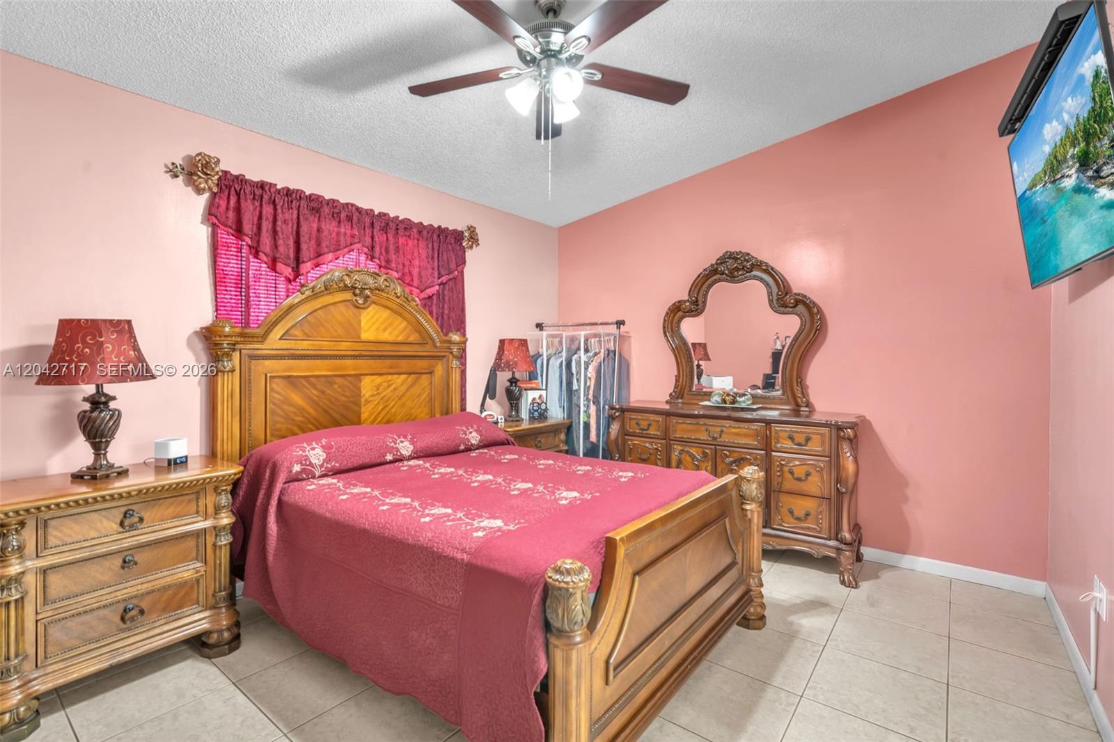 A bedroom features a wooden bed frame, matching dresser with mirror, and pink walls — 9018 NW 120th St # 133, Hialeah Gardens FL 33018, HIALEAH GARDENS, FL