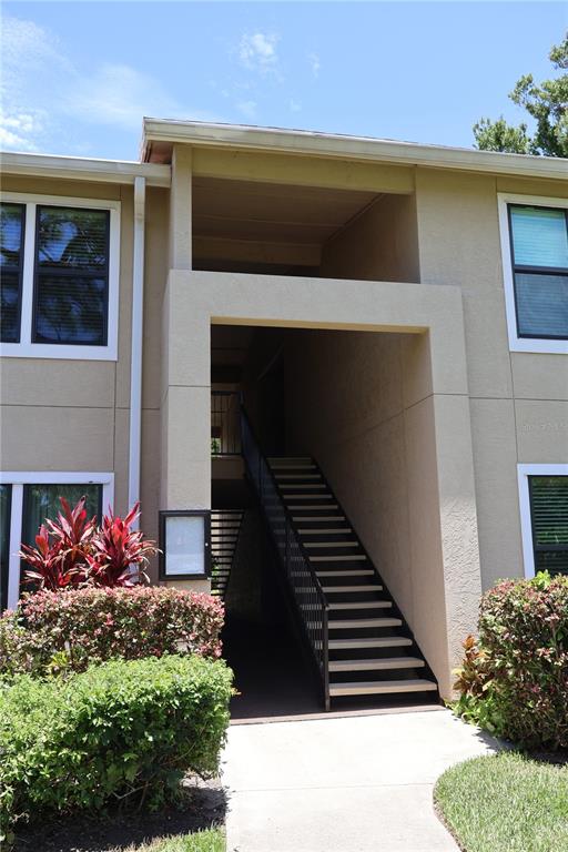 An exterior view of a two-story apartment building with an open-air staircase and landscaping — 4001 CROCKERS LAKE BOULEVARD UNIT 21, SARASOTA, FL