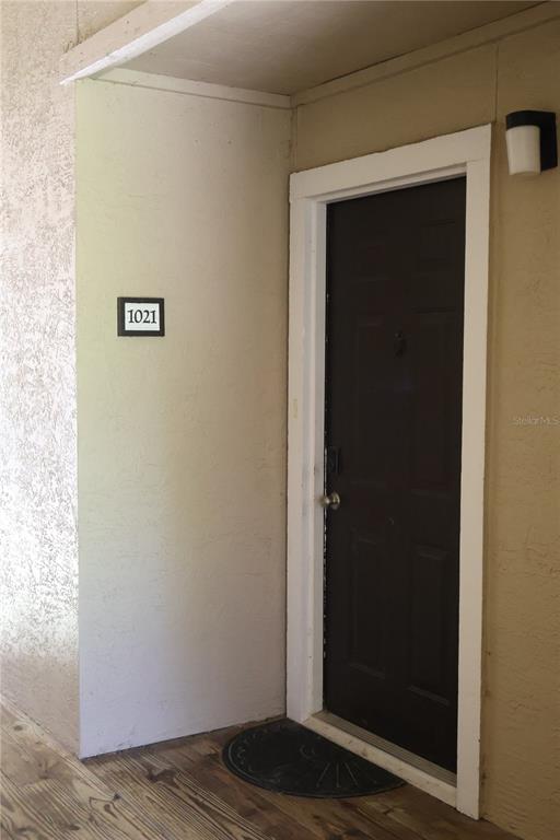 A dark brown front door with a number 1021 sign on the adjacent exterior wall — 4001 CROCKERS LAKE BOULEVARD UNIT 21, SARASOTA, FL