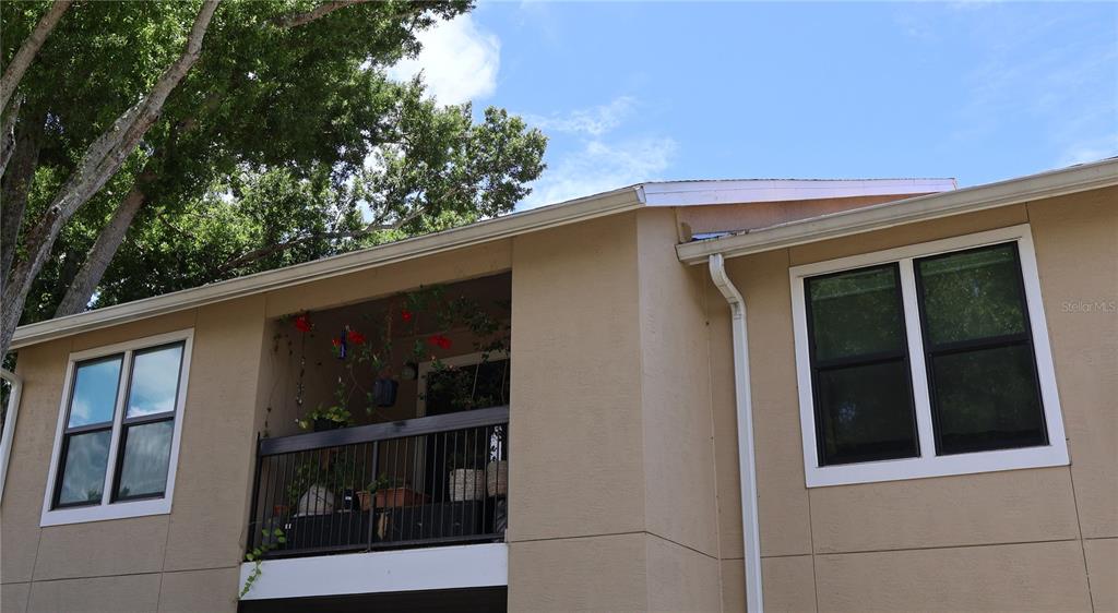 An exterior view of a tan building featuring a balcony with plants and two windows — 4001 CROCKERS LAKE BOULEVARD UNIT 21, SARASOTA, FL