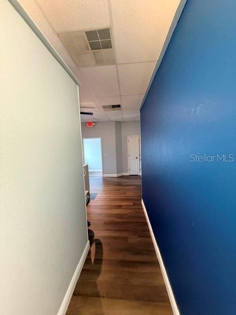 A hallway with wood-look flooring leads toward a doorway under a drop ceiling — 223 N COMMONWEALTH AVENUE SW, POLK CITY, FL