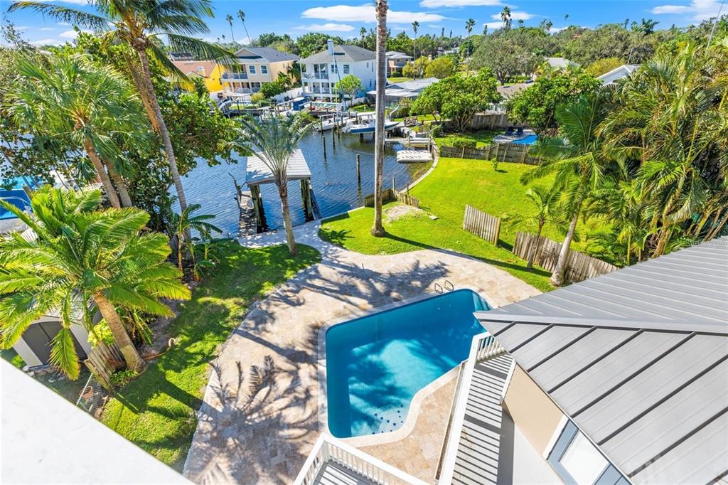 An aerial view of a backyard featuring a swimming pool, lawn, and a boat dock — 1902 ARROWHEAD DRIVE NE, ST PETERSBURG, FL