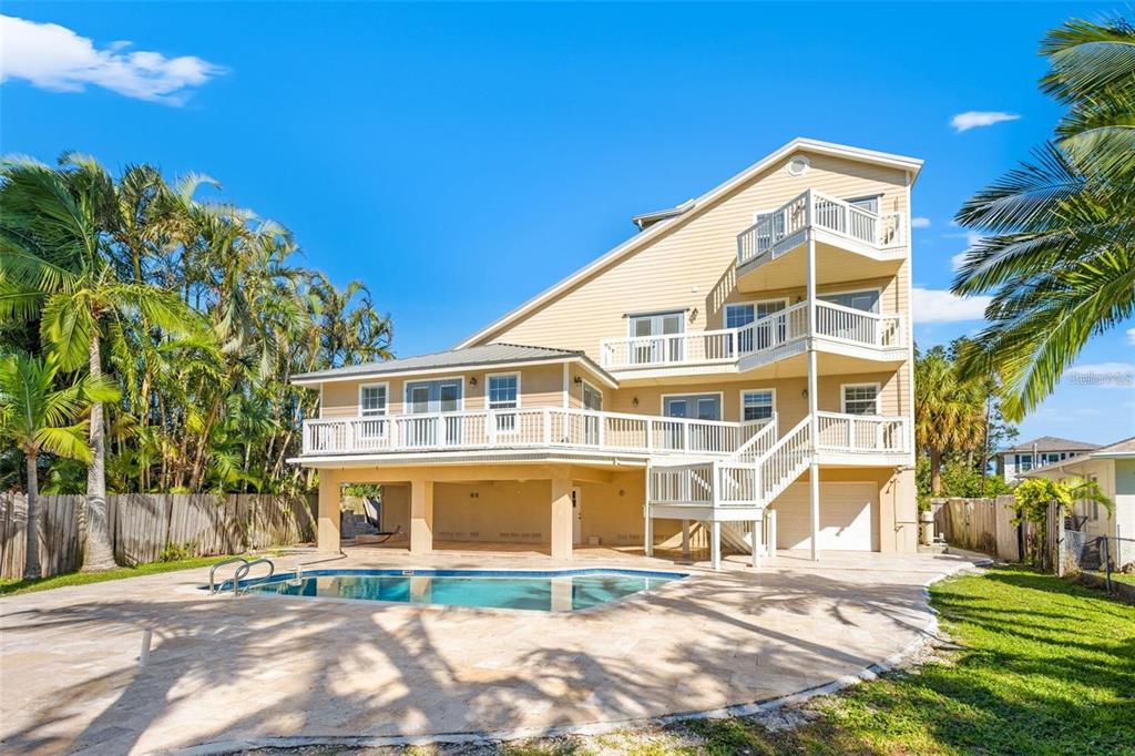 A three-story house with multiple balconies, a swimming pool, and a paved patio area — 1902 ARROWHEAD DRIVE NE, ST PETERSBURG, FL