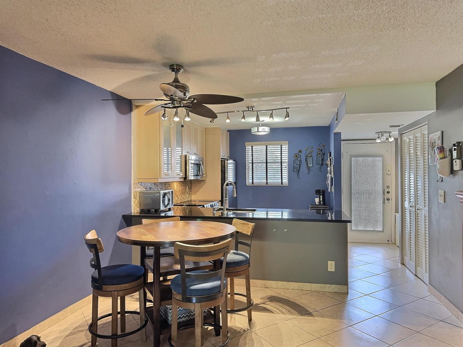 A kitchen with blue walls, light wood cabinets, a breakfast bar, and a dining table — 3150 Holiday Springs Boulevard # 204, Margate FL 33063, MARGATE, FL