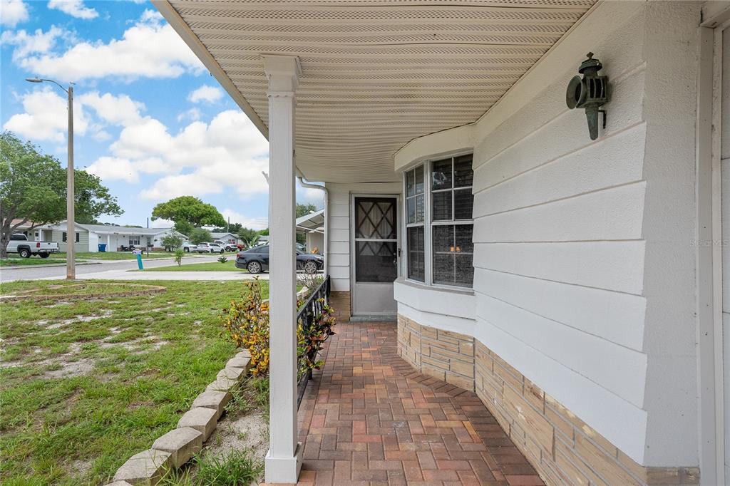 A covered front porch with brick pavers, a white support column, and a bay window — 3410 COLUMBUS DRIVE, HOLIDAY, FL