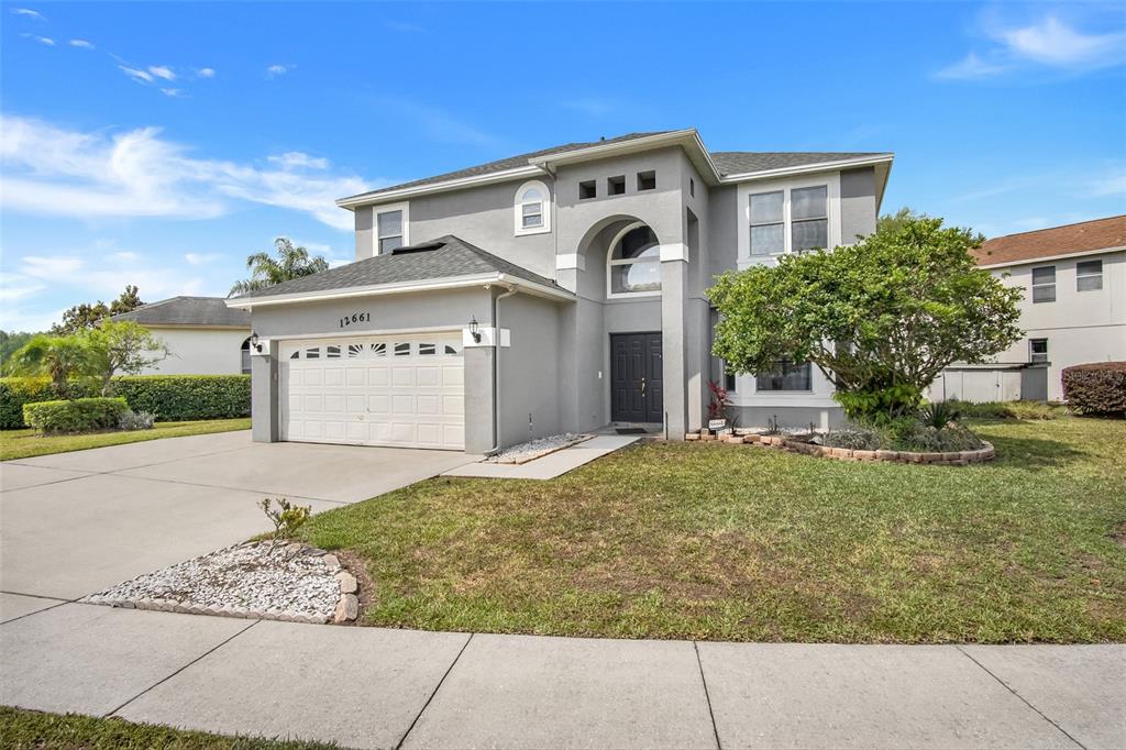 A two-story gray house features a two-car garage, a covered entryway, and a front lawn — 12661 ENCLAVE DRIVE, ORLANDO, FL