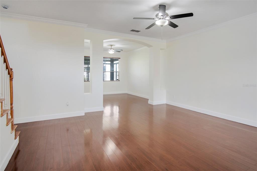 An empty living room features hardwood floors, white walls, and two ceiling fans — 12661 ENCLAVE DRIVE, ORLANDO, FL