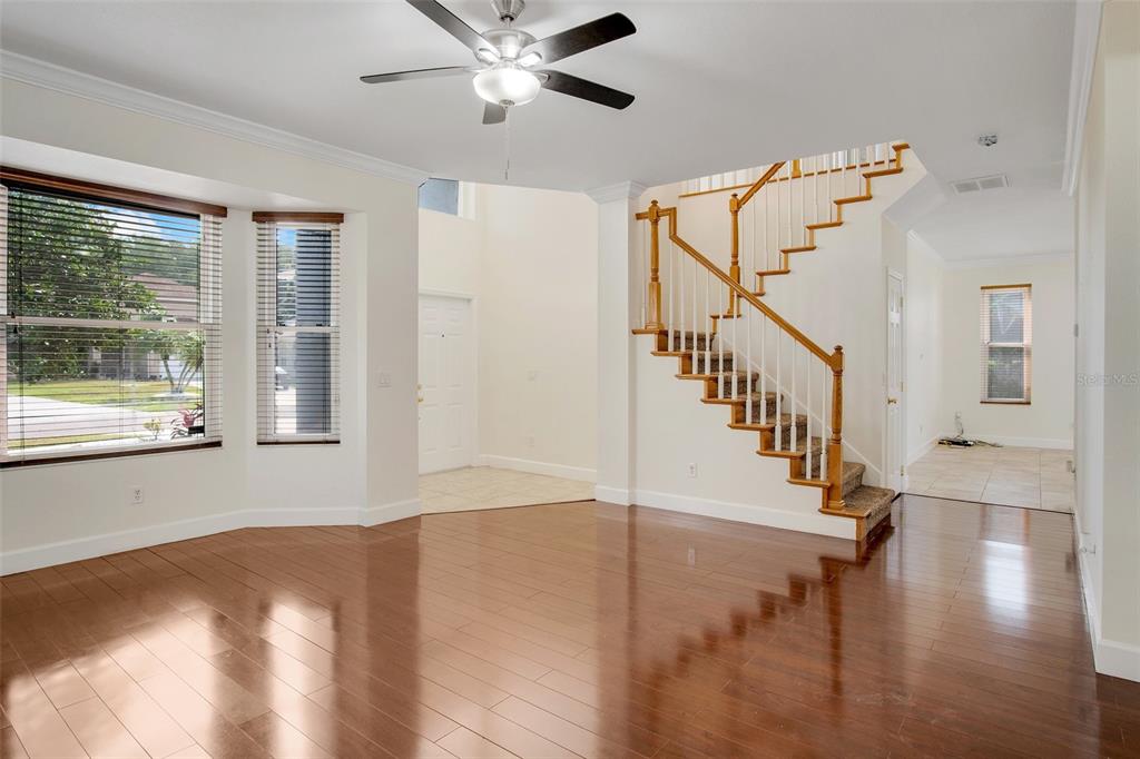 A living room with hardwood floors, a wooden staircase, and a ceiling fan — 12661 ENCLAVE DRIVE, ORLANDO, FL