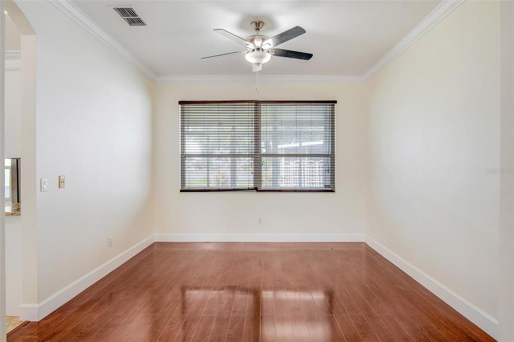 An empty dining room features hardwood floors, a ceiling fan, and a large window — 12661 ENCLAVE DRIVE, ORLANDO, FL