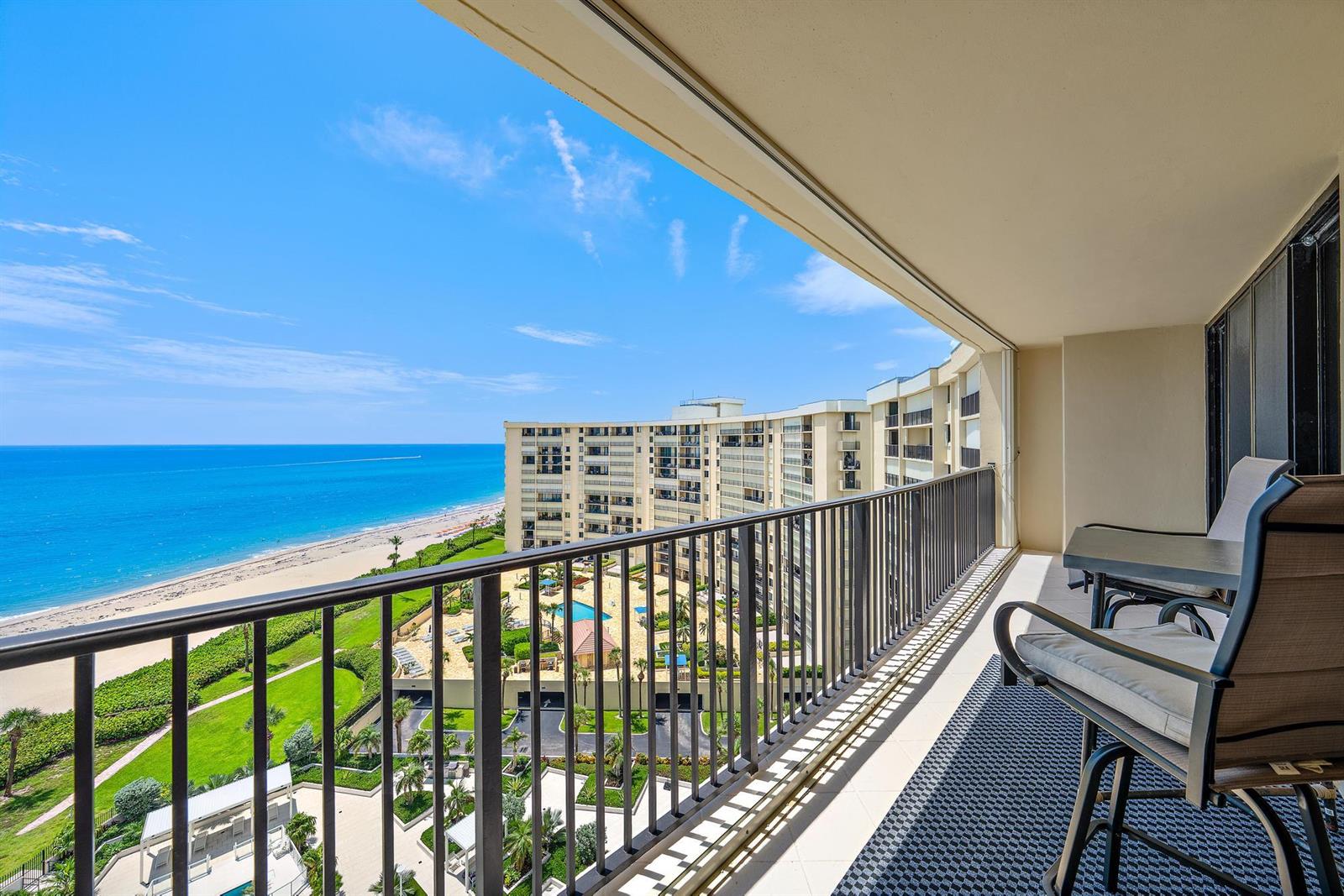 A balcony with a metal railing overlooks a beach, ocean, and a large apartment complex — 200 Ocean Trail Way # 1205, Jupiter FL 33477, JUPITER, FL