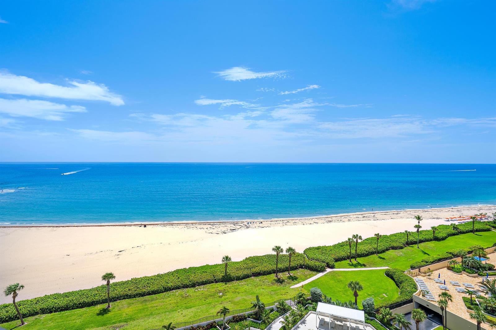 An elevated view of a sandy beach, ocean, and landscaped grounds with palm trees — 200 Ocean Trail Way # 1205, Jupiter FL 33477, JUPITER, FL