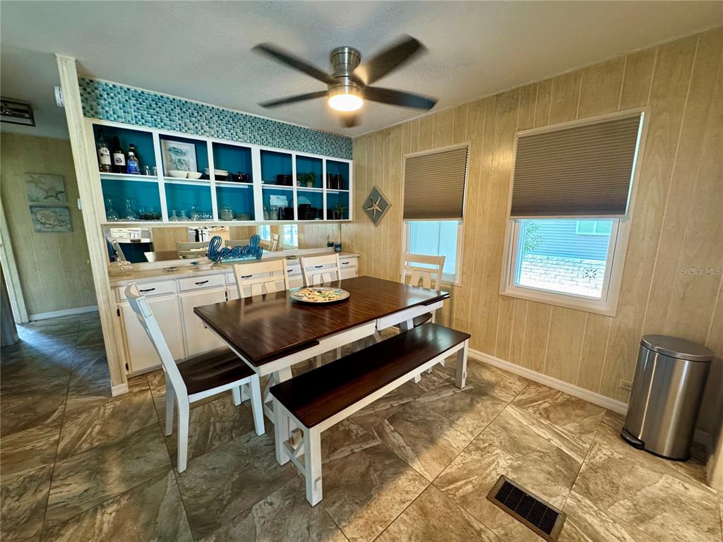 A dining room features a wooden table with a bench, built-in shelving, and tiled flooring — 203 ESTRADA, NORTH PORT, FL