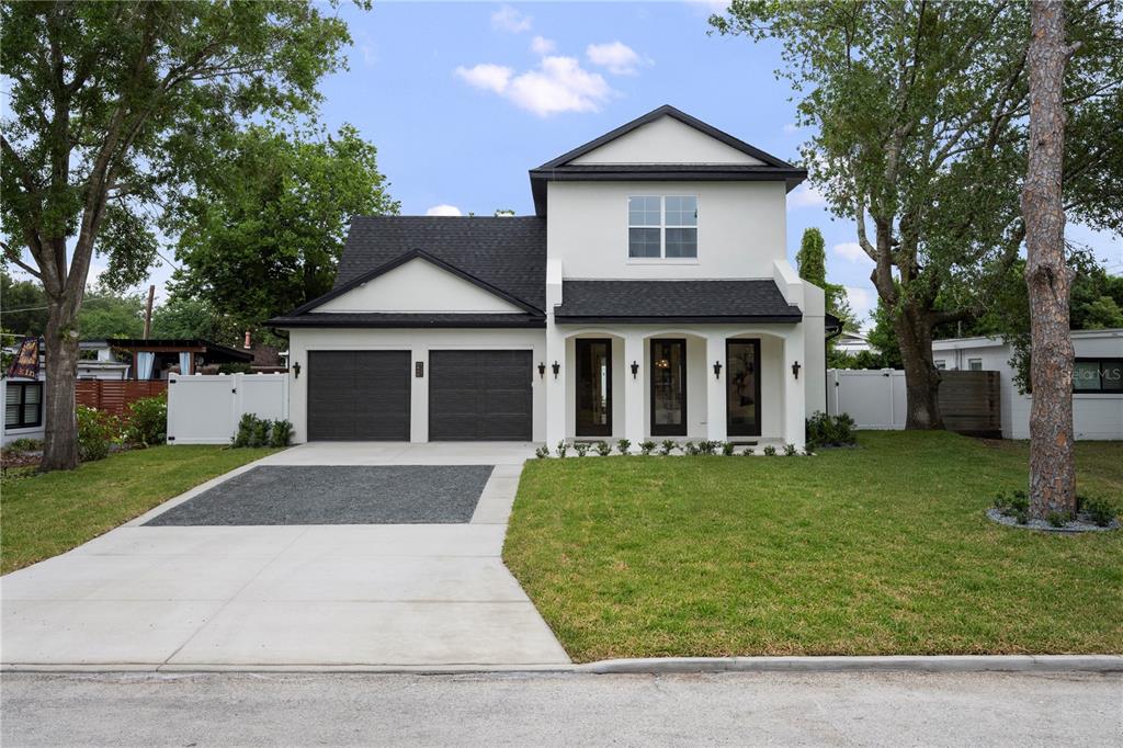 A two-story house with a white stucco exterior, black roof, and a two-car garage — 2430 CHANTILLY AVENUE, WINTER PARK, FL