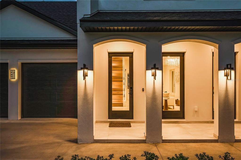 The exterior of a modern home features a garage, a covered entryway, and glass doors — 2430 CHANTILLY AVENUE, WINTER PARK, FL