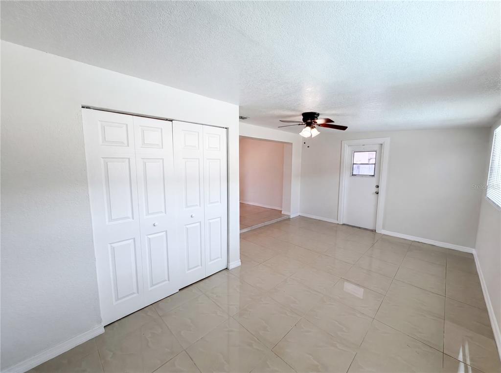 A room with white walls, tile flooring, a ceiling fan, a closet, and a door — 15525 BEDFORD CIRCLE E, CLEARWATER, FL