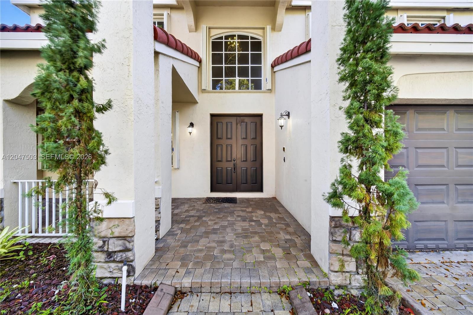 The exterior entrance features a paved walkway, double front doors, and two tall evergreen trees — 1325 Chenille Cir, Weston FL 33327, WESTON, FL