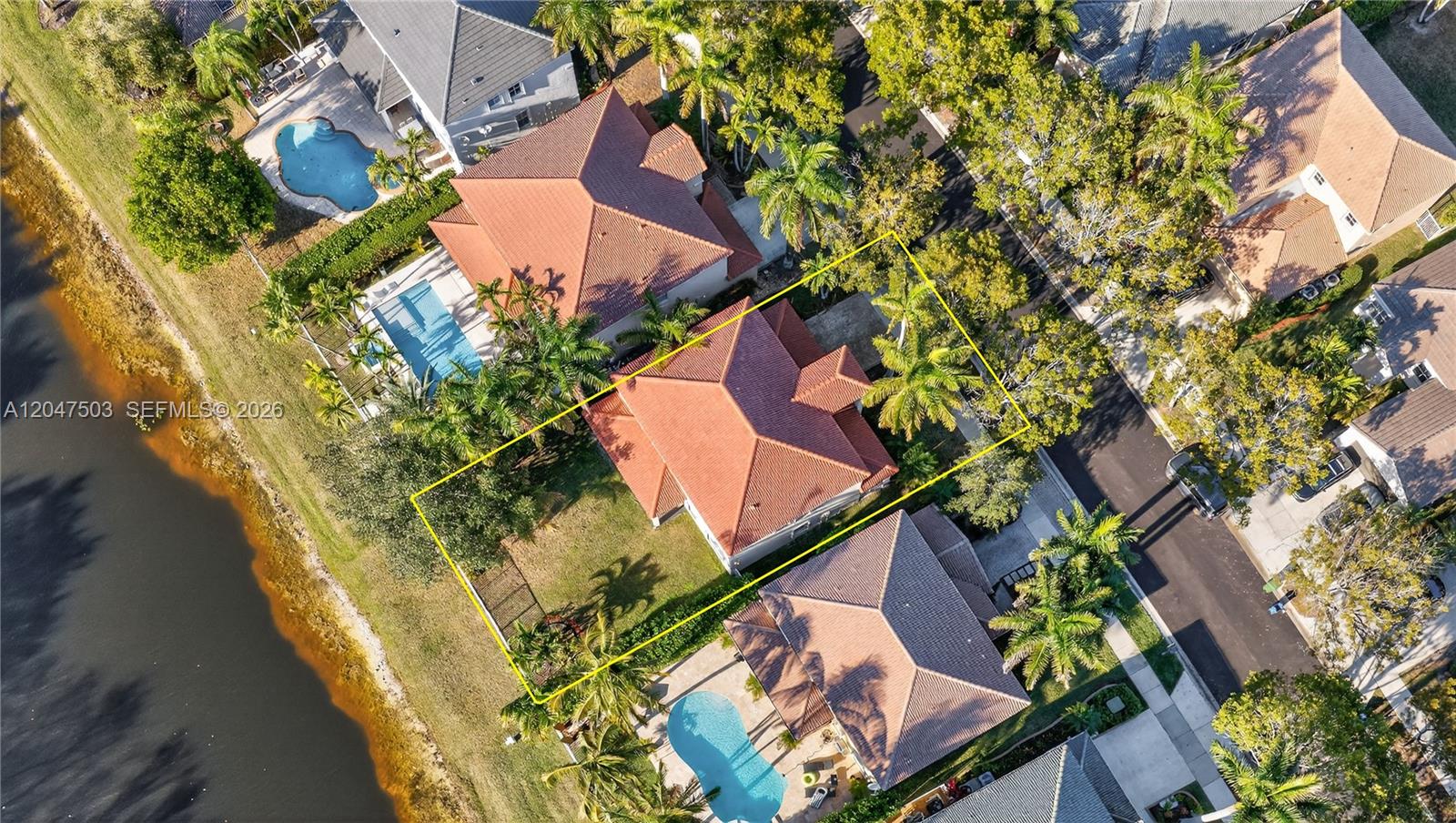 An aerial view shows a residential house with a red tile roof and backyard lawn — 1325 Chenille Cir, Weston FL 33327, WESTON, FL