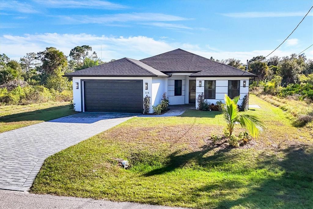 A single-story house with a dark roof, white exterior, and a paved driveway — 115 GREEN PINE PARK, ROTONDA WEST, FL