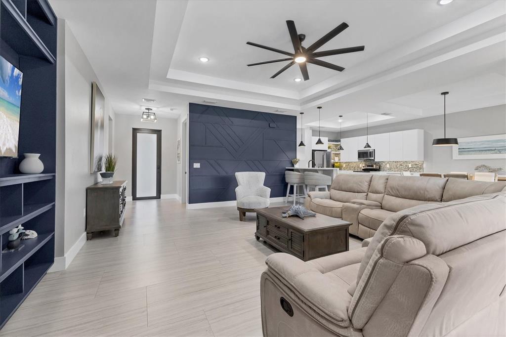 A living room features a blue accent wall, light wood floors, and a sectional sofa — 115 GREEN PINE PARK, ROTONDA WEST, FL
