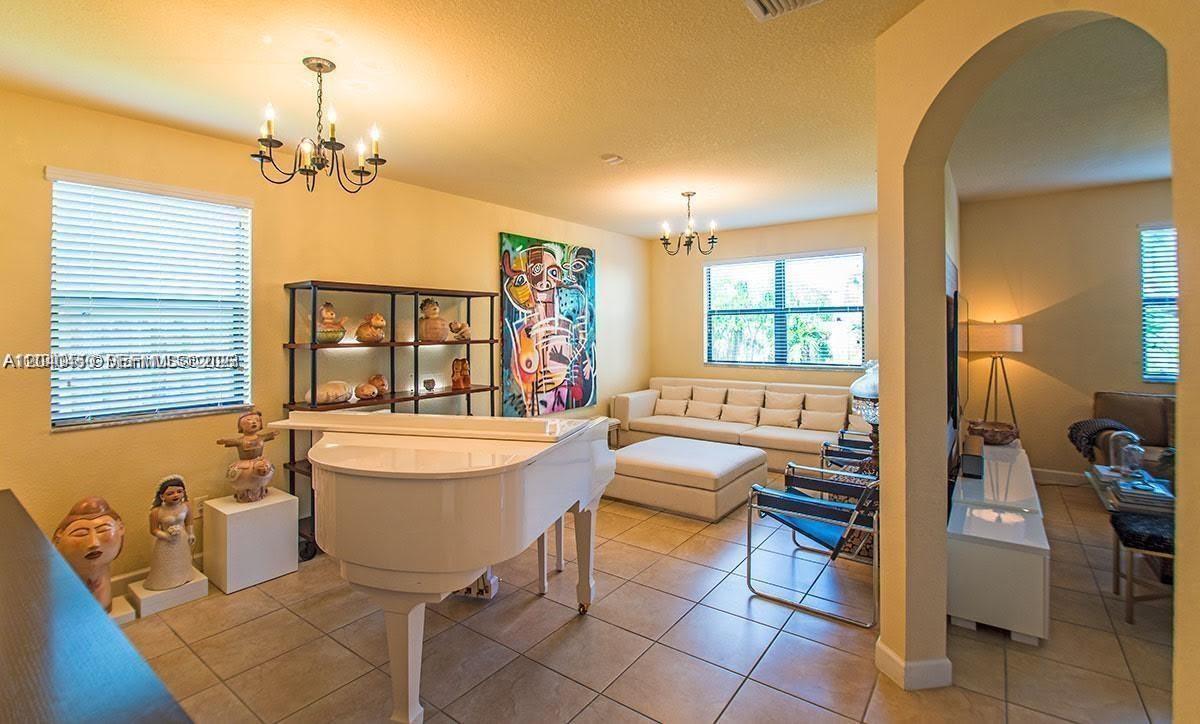A living room features a white grand piano, tile flooring, and a large abstract painting — 1522 SW 144th Ave, Miami FL 33184, MIAMI, FL