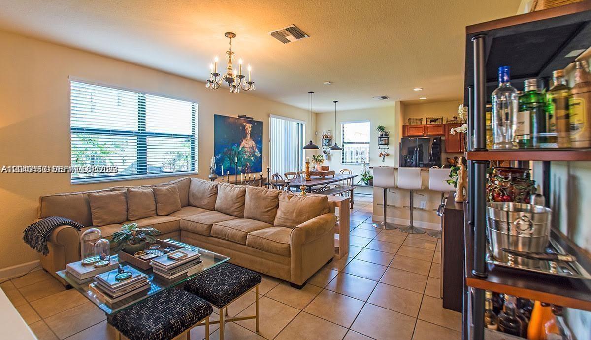 An open-concept living and dining area features a large sectional sofa and tile flooring — 1522 SW 144th Ave, Miami FL 33184, MIAMI, FL